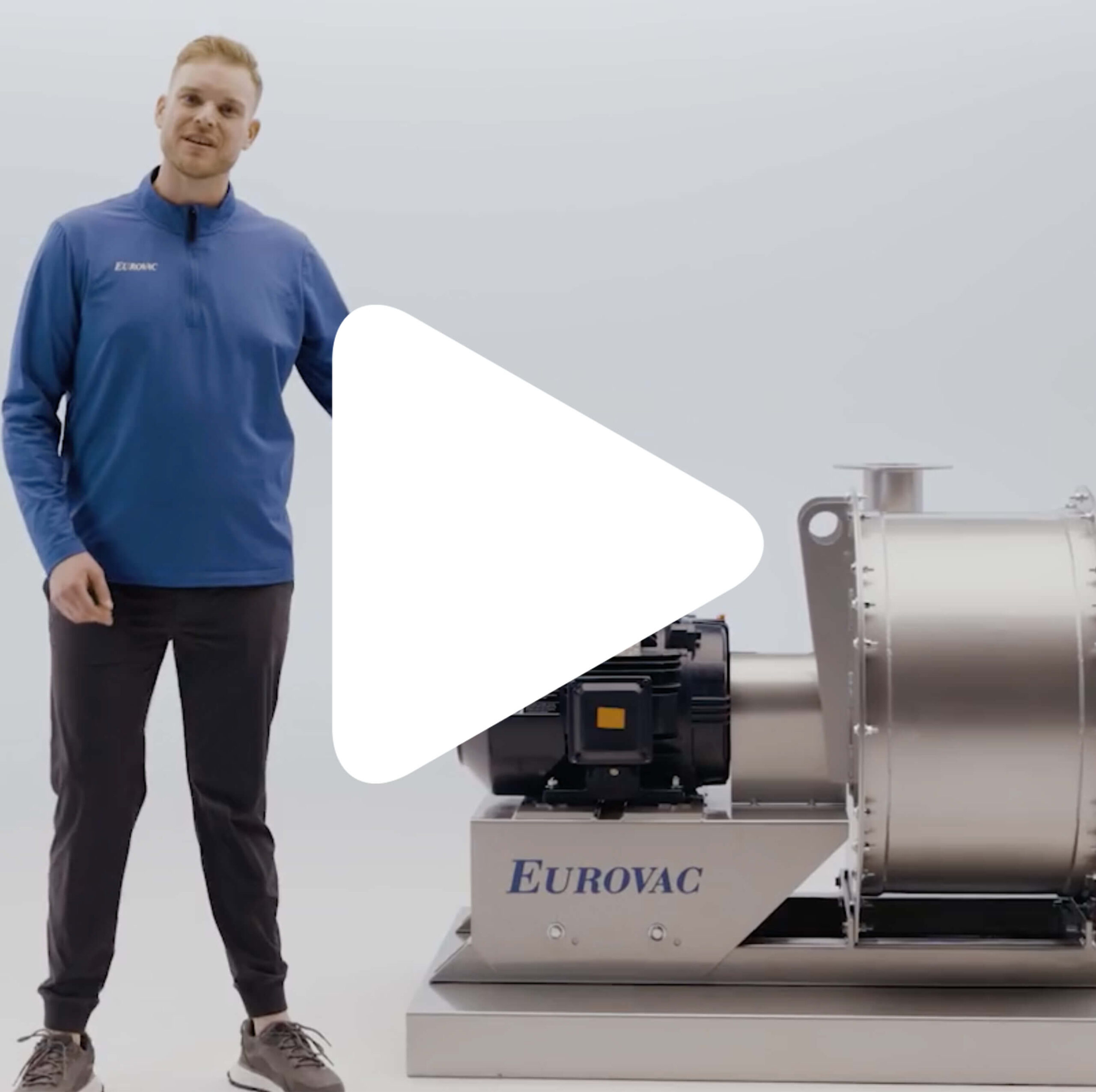 A person stands next to a large industrial machine labeled "Eurovac." The person wears a blue long-sleeve shirt and dark pants. A large white play button overlays the center of the image.