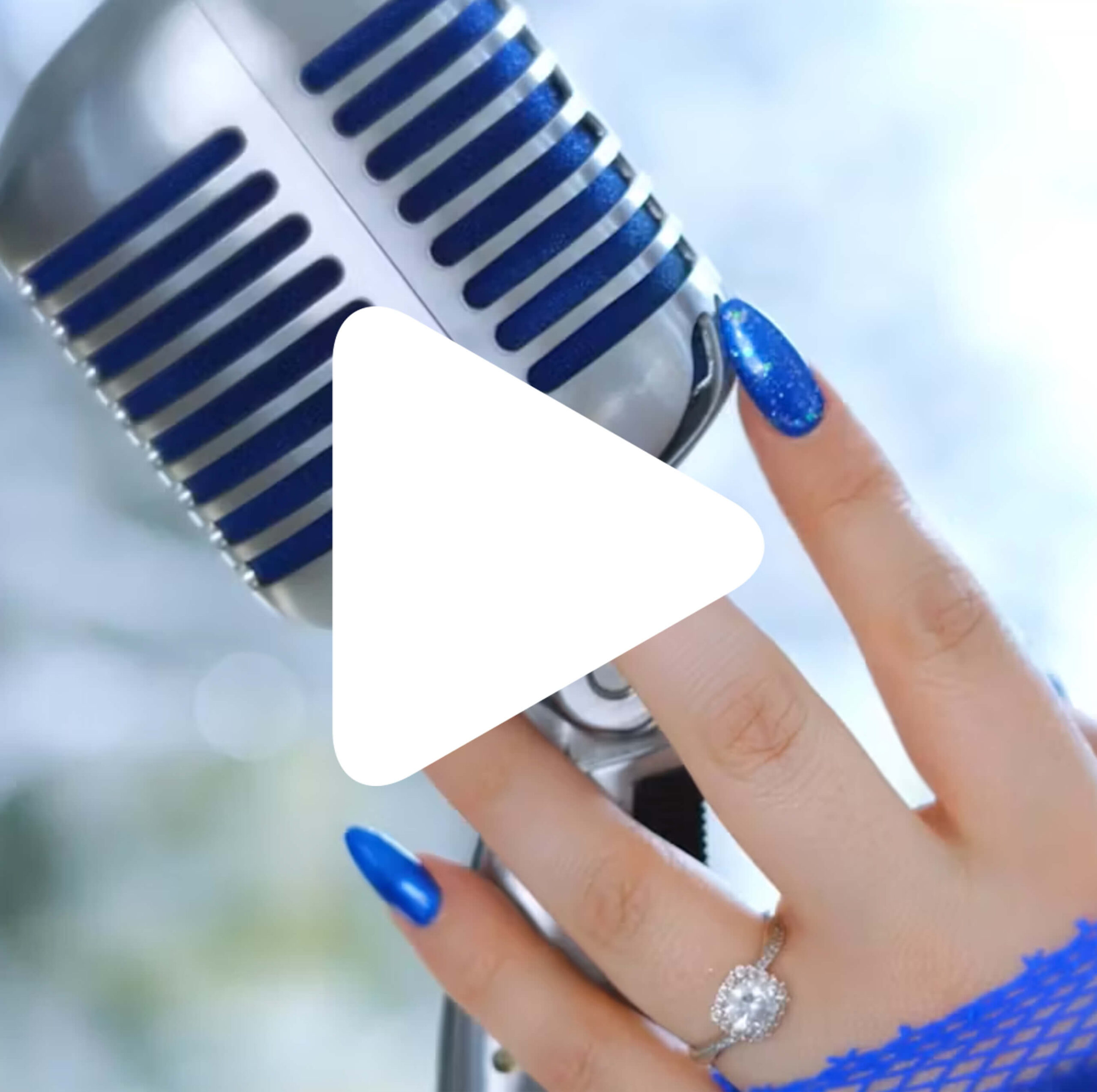 A hand with blue nail polish and a diamond ring holds a vintage-style silver microphone. The person is wearing a blue fishnet glove. A white play button icon is overlaid on the image.